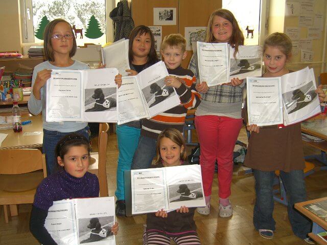 Ein paar Kinder zeigen ihre TeilnehmerInnen-Mappen.